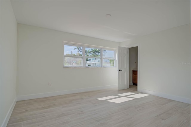 spare room featuring light wood-type flooring and baseboards