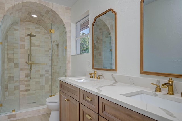 full bath with a stall shower, a sink, double vanity, and toilet