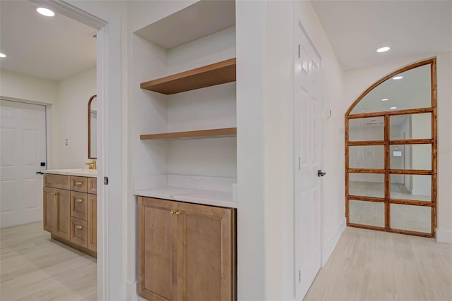 hall featuring light wood finished floors, baseboards, and recessed lighting