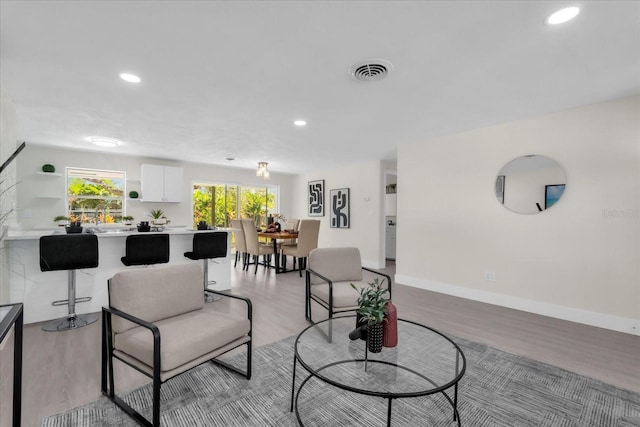 living area with baseboards, visible vents, recessed lighting, and light wood-type flooring