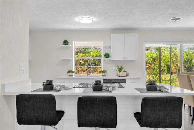 kitchen with a kitchen bar, a sink, open shelves, and visible vents