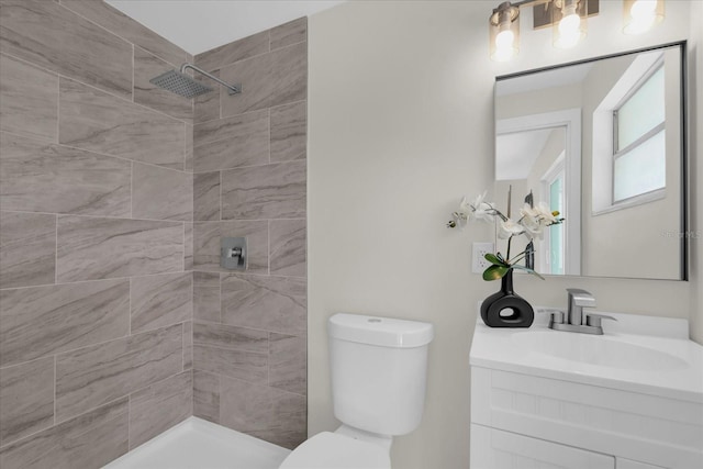 full bathroom featuring toilet, a tile shower, and vanity