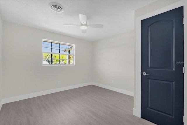 empty room with baseboards, ceiling fan, visible vents, and wood finished floors