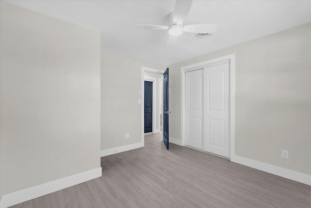 unfurnished bedroom featuring a closet, baseboards, wood finished floors, and a ceiling fan