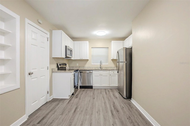 3645 6th St S, Saint Petersburg, FL 33705 - kitchen featuring white cabinetry, light wood-type flooring, stainless steel appliances, baseboards, and a sink