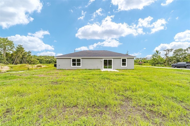 rear view of property featuring stucco siding and a yard