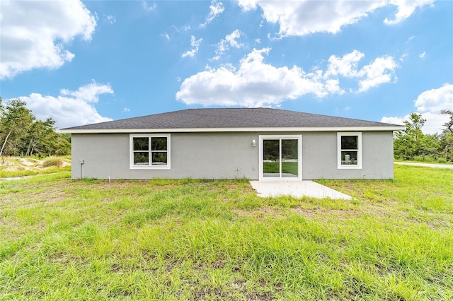 rear view of property with a yard, stucco siding, and a patio area