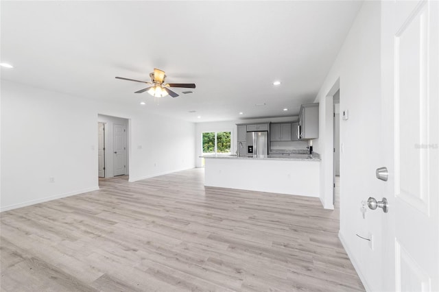 unfurnished living room featuring baseboards, ceiling fan, light wood-type flooring, recessed lighting, and a sink