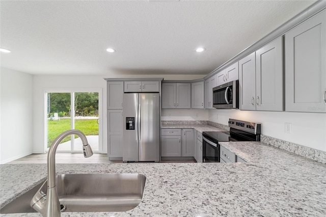 kitchen with a sink, stainless steel appliances, recessed lighting, and gray cabinets