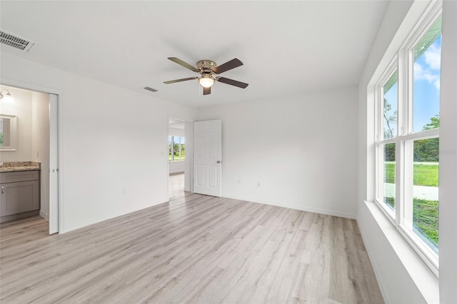 empty room featuring visible vents, ceiling fan, baseboards, and light wood-style floors