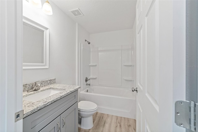 full bathroom with visible vents, toilet, vanity, wood finished floors, and a textured ceiling