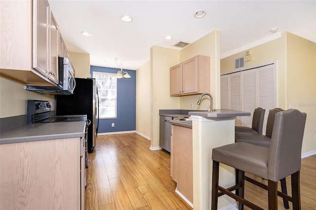 6274 Bristol Channel Way, Orlando, FL 32829 - kitchen featuring light brown cabinetry, a sink, a kitchen breakfast bar, stainless steel appliances, and a peninsula