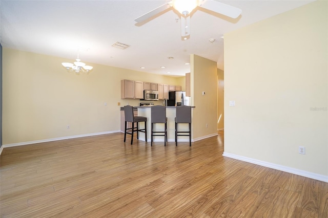 6274 Bristol Channel Way, Orlando, FL 32829 - kitchen featuring a breakfast bar area, light wood-style floors, open floor plan, and stainless steel appliances