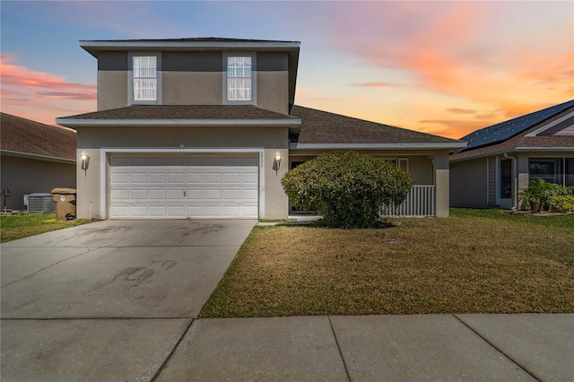 traditional-style home with driveway, central air condition unit, stucco siding, an attached garage, and a front lawn