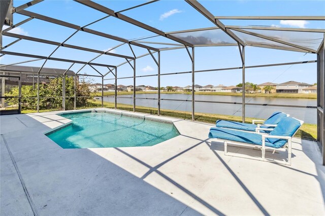 outdoor pool with glass enclosure, a water view, and a patio area