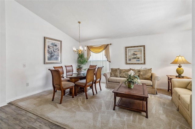 dining space featuring light wood finished floors, baseboards, vaulted ceiling, and an inviting chandelier