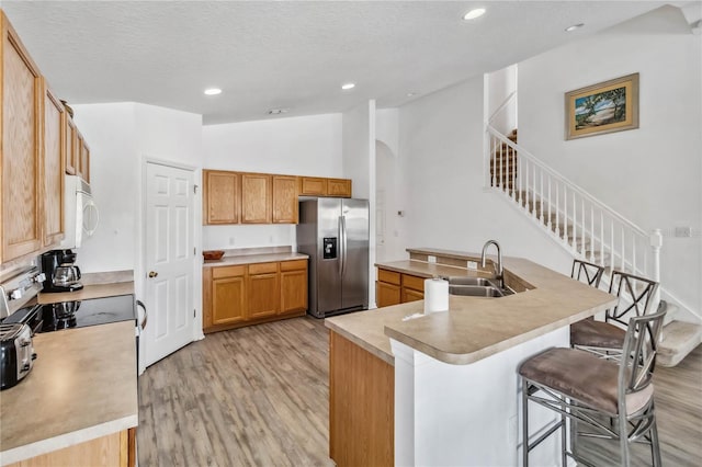 kitchen featuring a breakfast bar, appliances with stainless steel finishes, lofted ceiling, light wood-style floors, and recessed lighting