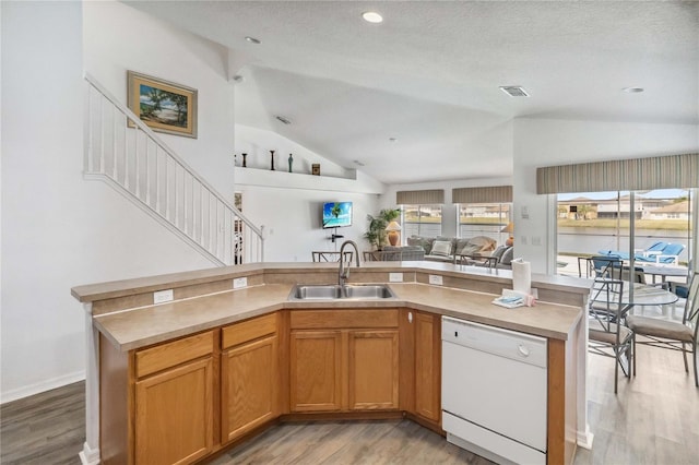 kitchen featuring a sink, light wood-style floors, open floor plan, white dishwasher, and vaulted ceiling