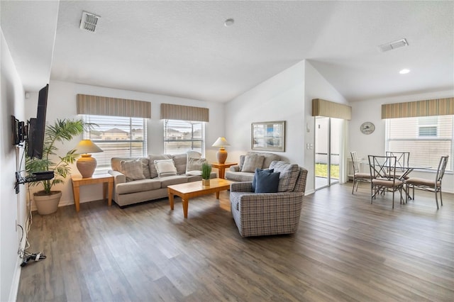 living room with plenty of natural light, visible vents, vaulted ceiling, and wood finished floors