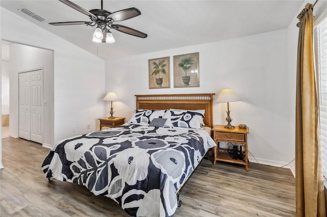 bedroom with a closet, visible vents, vaulted ceiling, and wood finished floors