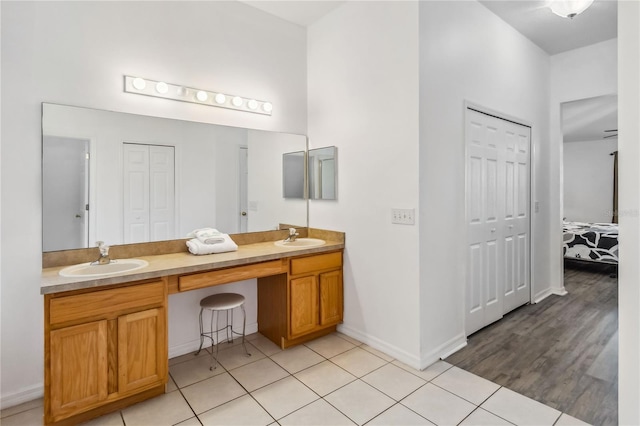 full bathroom featuring a closet, double vanity, a sink, and tile patterned floors
