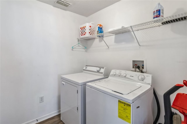 laundry area with baseboards, visible vents, washer and dryer, laundry area, and wood finished floors
