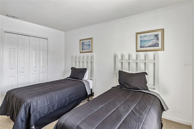carpeted bedroom featuring a closet, a textured ceiling, and visible vents