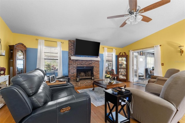 living room featuring wood finished floors, lofted ceiling, a fireplace, and ceiling fan