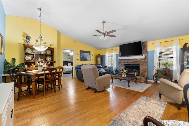living room featuring a brick fireplace, light wood-type flooring, a ceiling fan, and plenty of natural light