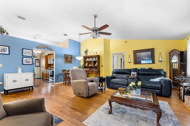 living room with visible vents, baseboards, wood finished floors, a ceiling fan, and lofted ceiling