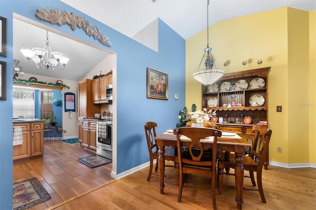 dining area featuring lofted ceiling, light wood-type flooring, and a chandelier