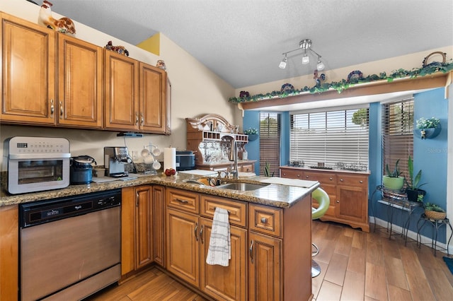kitchen with dishwasher, a sink, a peninsula, and brown cabinets