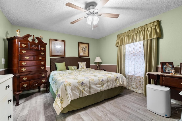 bedroom with light wood-type flooring, a ceiling fan, and a textured ceiling