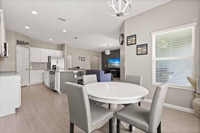 dining room with light wood-style flooring, baseboards, visible vents, arched walkways, and recessed lighting