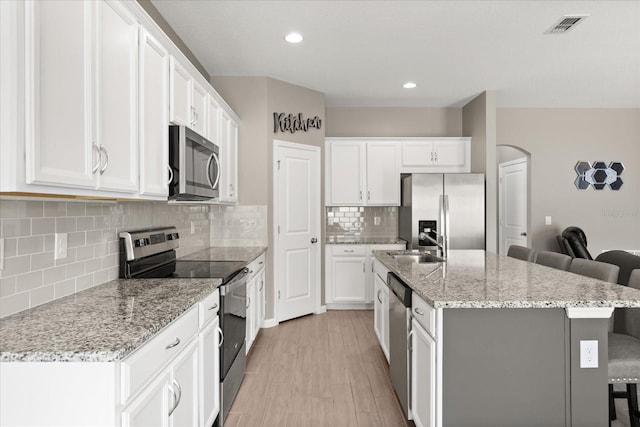 1174 Tupelo Trl, Haines City, FL 33844 - kitchen with stainless steel appliances, a kitchen breakfast bar, an island with sink, white cabinetry, and recessed lighting