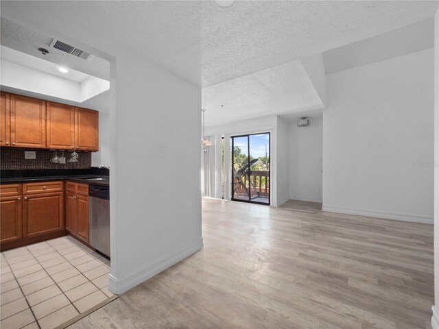 1092 E Michigan St Unit 1, Orlando, FL 32806 - kitchen featuring stainless steel dishwasher, baseboards, light wood finished floors, backsplash, and dark countertops