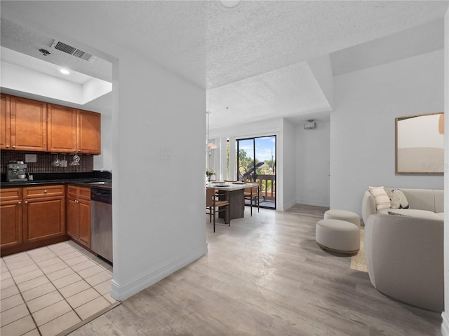 1092 E Michigan St Unit 1, Orlando, FL 32806 - kitchen featuring stainless steel dishwasher, baseboards, light wood-style flooring, brown cabinetry, and a textured ceiling