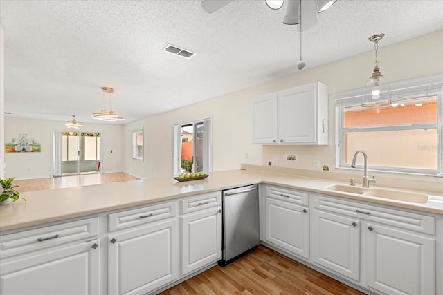 kitchen featuring white cabinetry, decorative light fixtures, a sink, visible vents, and a peninsula