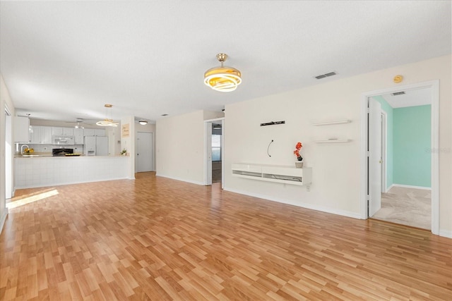 unfurnished living room featuring baseboards, light wood-style flooring, and visible vents