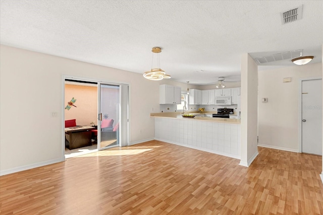 kitchen with light countertops, light wood finished floors, black electric range oven, visible vents, and white microwave