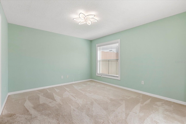empty room with baseboards, a textured ceiling, and carpet