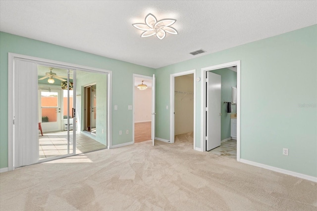 unfurnished bedroom with visible vents, carpet, baseboards, french doors, and a walk in closet