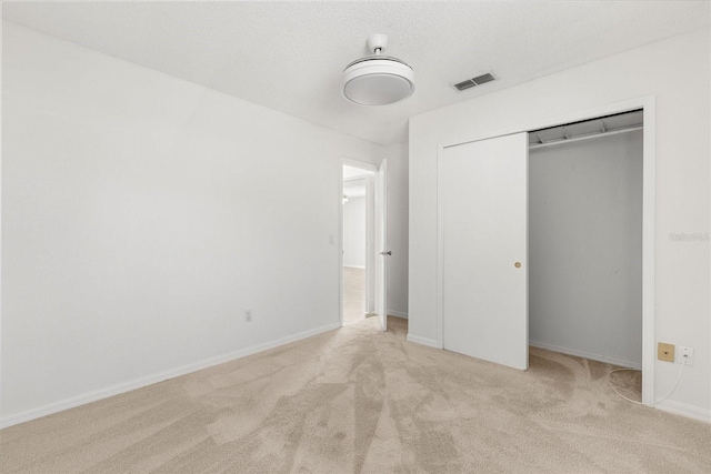 unfurnished bedroom with a closet, carpet floors, a textured ceiling, baseboards, and visible vents