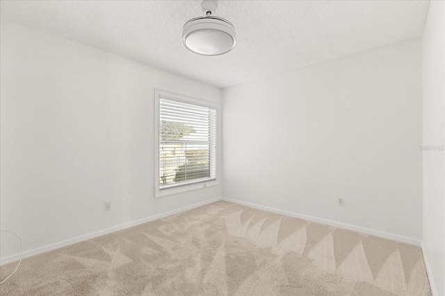 empty room featuring baseboards, carpet flooring, and a textured ceiling