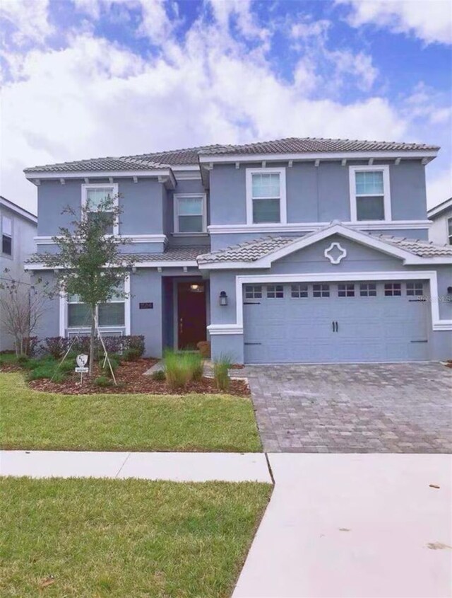 1584 Plunker Dr, Davenport, FL 33896 - view of front of home featuring stucco siding, driveway, a front yard, an attached garage, and a tiled roof