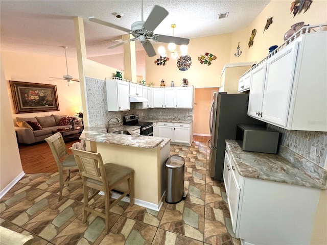 4638 River Ridge Drive, Leesburg, FL 34748 - kitchen with backsplash, ceiling fan, under cabinet range hood, stainless steel electric range oven, and a peninsula