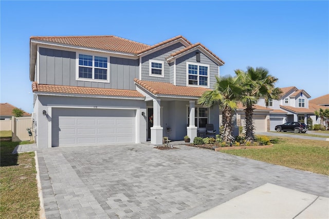 1158 Oak Bluff Dr, Davenport, FL 33837 - view of front of property featuring a tiled roof, decorative driveway, a porch, an attached garage, and board and batten siding