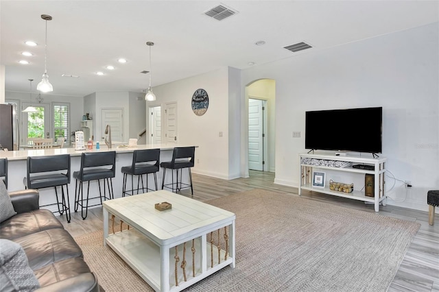 living room with arched walkways, baseboards, visible vents, and recessed lighting