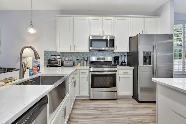 kitchen featuring tasteful backsplash, light stone counters, appliances with stainless steel finishes, and white cabinets