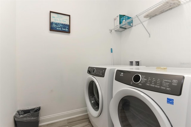 washroom with baseboards, separate washer and dryer, wood finished floors, and laundry area